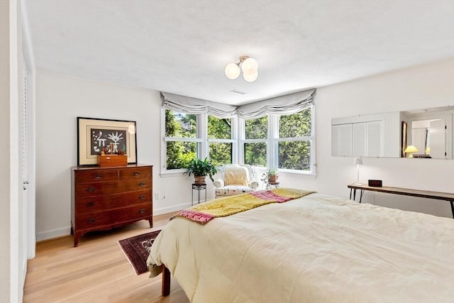 bedroom featuring multiple windows, wood finished floors, and baseboards