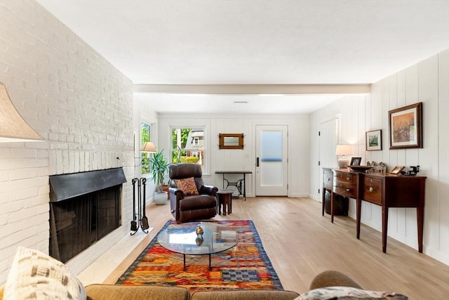 living room featuring light wood-style floors, a brick fireplace, and baseboards