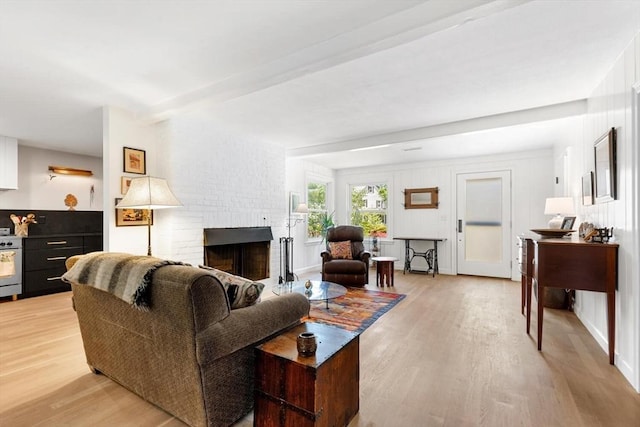 living room featuring light wood-type flooring and a brick fireplace