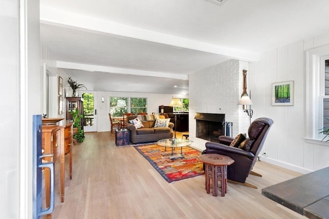 living area featuring wood finished floors, a fireplace, and beam ceiling