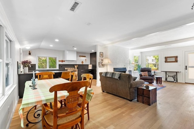dining space with light wood finished floors, a fireplace, vaulted ceiling, and recessed lighting