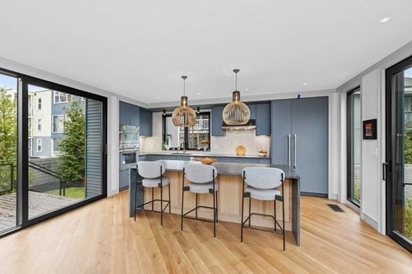 kitchen with light wood-style floors, decorative backsplash, and a kitchen breakfast bar