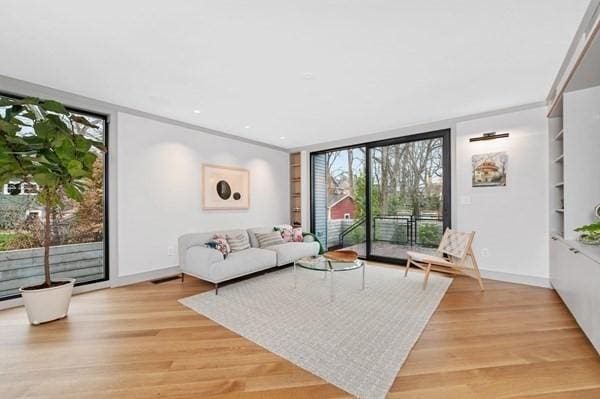 living room featuring light wood-style flooring, expansive windows, baseboards, and built in features