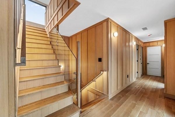 stairway with wood walls and wood finished floors