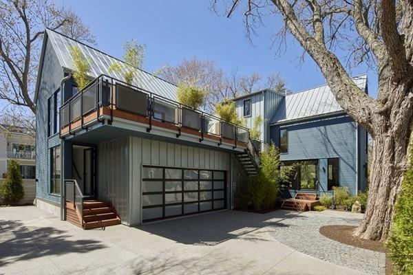 back of property with metal roof, concrete driveway, a standing seam roof, and an attached garage