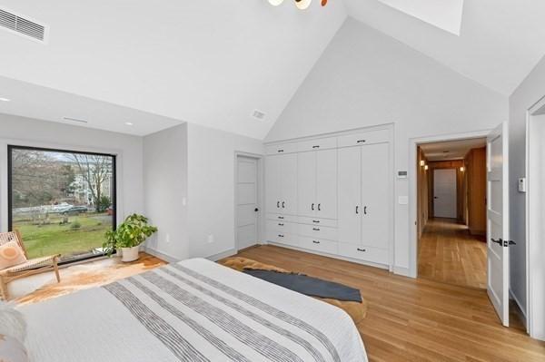 bedroom with light wood finished floors, baseboards, visible vents, and high vaulted ceiling