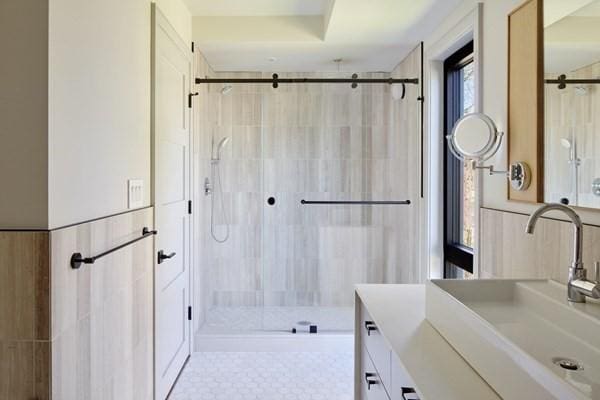 full bathroom with a stall shower, wainscoting, and vanity