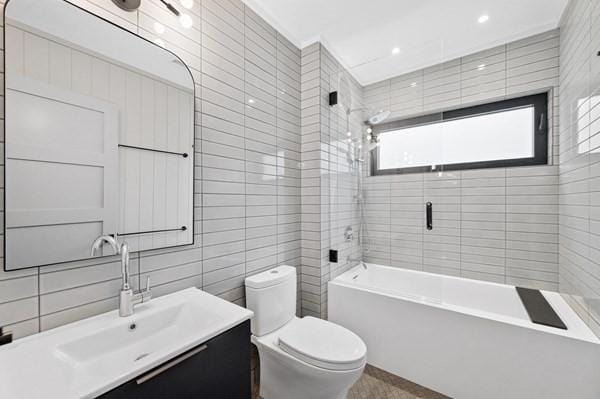 full bath with toilet, vanity, shower / tub combination, and tile walls