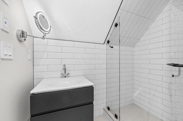 full bath featuring lofted ceiling, a shower stall, and vanity