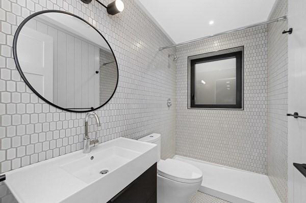 bathroom with tile walls, backsplash, toilet, vanity, and tiled shower