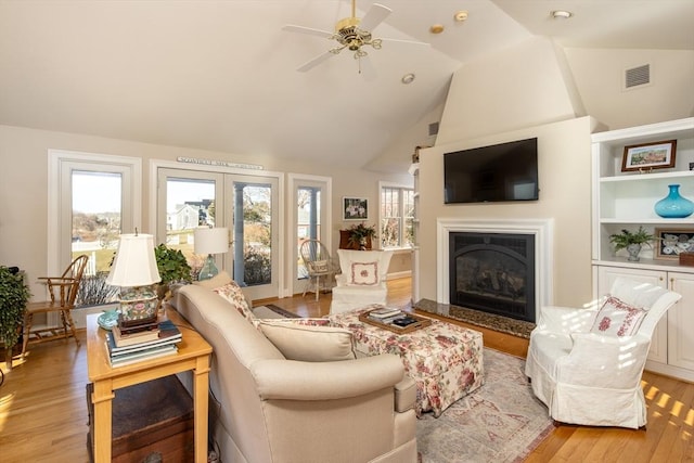 living room featuring ceiling fan, vaulted ceiling, and light wood-type flooring