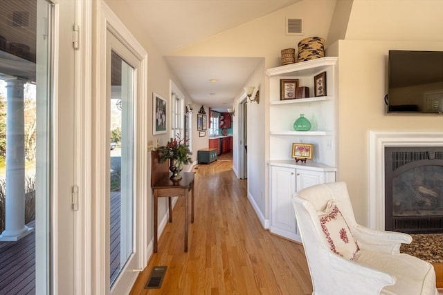 hall with light hardwood / wood-style flooring and lofted ceiling