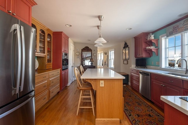 kitchen featuring a kitchen breakfast bar, stainless steel appliances, sink, wood-type flooring, and a center island