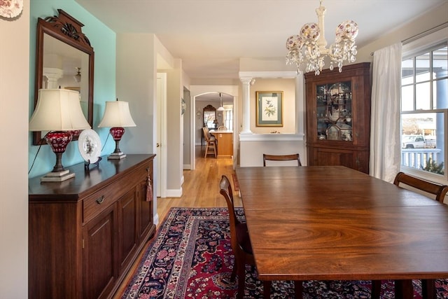 dining room with a chandelier, light wood-type flooring, and decorative columns