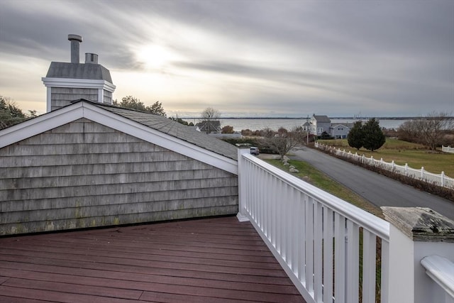 deck at dusk featuring a water view