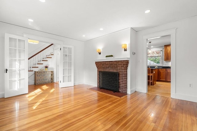12 Moreland Rd, Quincy, MA 02169 - unfurnished living room featuring french doors, light wood-style flooring, stairway, a brick fireplace, and recessed lighting