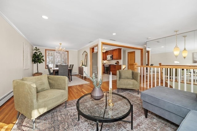 living room featuring ornamental molding, a notable chandelier, baseboard heating, and light hardwood / wood-style flooring