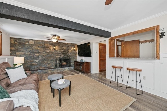 living room with hardwood / wood-style flooring, a fireplace, crown molding, and ceiling fan