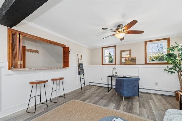 sitting room featuring crown molding, a baseboard heating unit, and a wealth of natural light