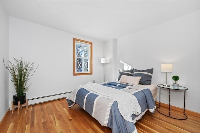 bedroom with hardwood / wood-style flooring and a baseboard heating unit