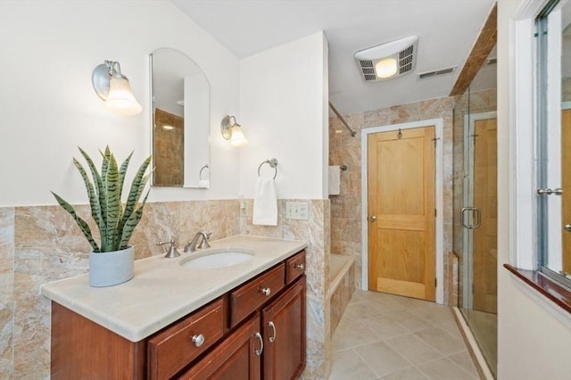 bathroom with vanity, tile patterned flooring, tile walls, and walk in shower