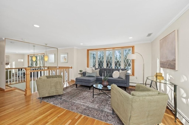 living room featuring ornamental molding, a baseboard heating unit, and light hardwood / wood-style floors