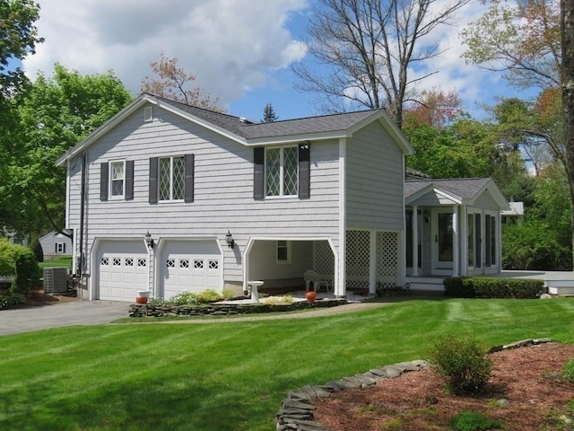 view of front of home featuring cooling unit, a garage, a front lawn, and a sunroom