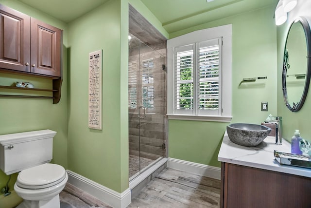 bathroom with hardwood / wood-style floors, a shower with door, toilet, and vanity