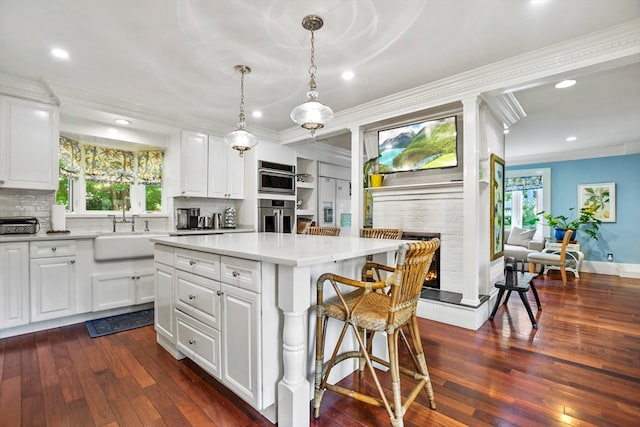 kitchen featuring a stone fireplace, a center island, and white cabinets