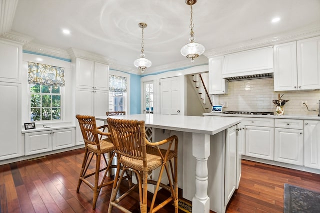 kitchen with white cabinetry, a center island, decorative light fixtures, and dark hardwood / wood-style flooring