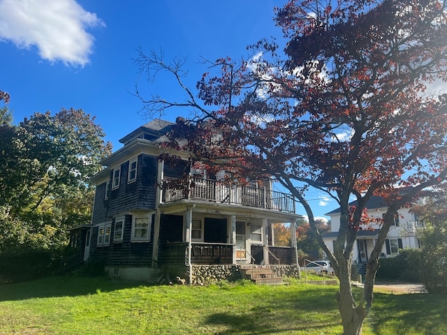 view of front of home featuring a balcony and a front lawn