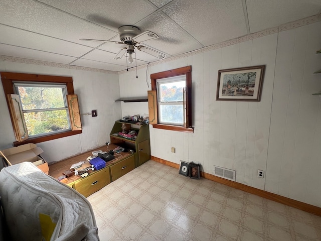 interior space with ceiling fan, a wealth of natural light, and a paneled ceiling