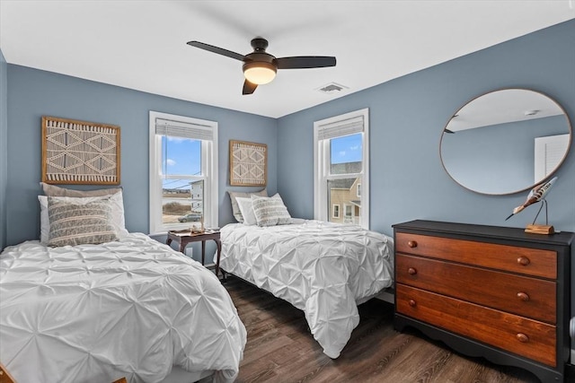 bedroom with ceiling fan, multiple windows, visible vents, and dark wood-type flooring