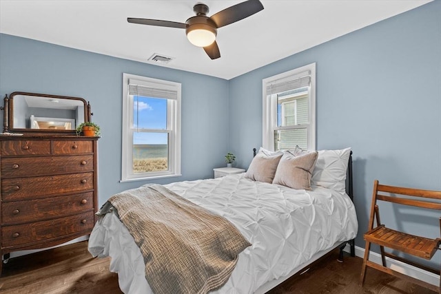 bedroom with ceiling fan, visible vents, and wood finished floors