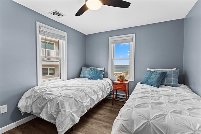 bedroom with visible vents, a baseboard heating unit, multiple windows, and wood finished floors