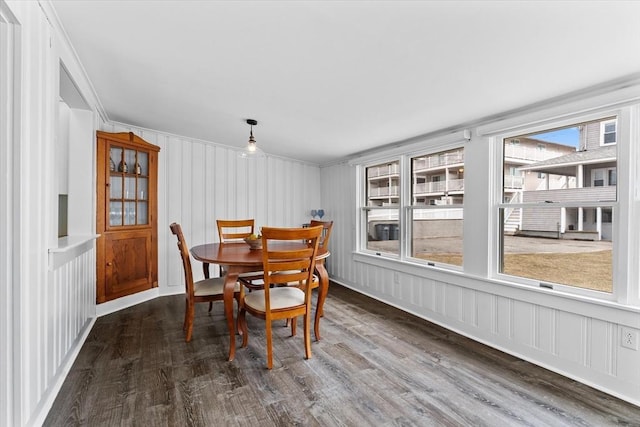 dining area featuring ornamental molding, a decorative wall, and wood finished floors