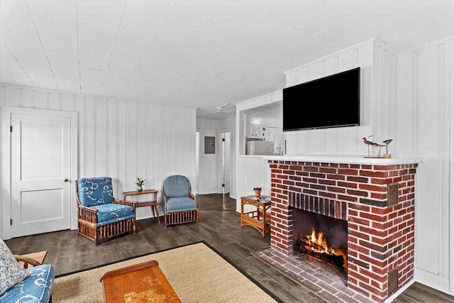 living area with a decorative wall, a brick fireplace, and wood finished floors