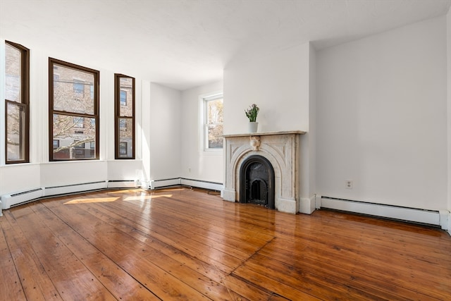 unfurnished living room featuring wood-type flooring and a baseboard heating unit