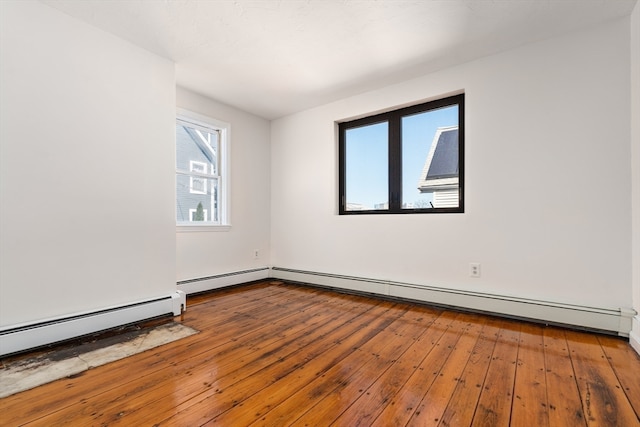 unfurnished room featuring hardwood / wood-style floors and a baseboard heating unit