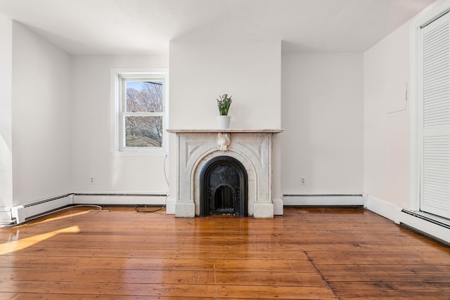 unfurnished living room featuring baseboard heating and wood-type flooring