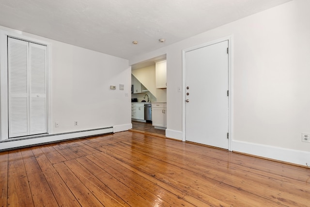 spare room featuring a baseboard heating unit and light hardwood / wood-style flooring