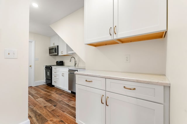 kitchen with white cabinetry, sink, stainless steel appliances, light stone counters, and dark hardwood / wood-style flooring