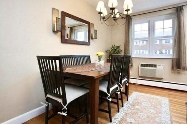 4 Emerson Gardens Rd Unit 4, Lexington, MA 02420 - dining space featuring a chandelier, baseboards, a wall unit AC, wood finished floors, and baseboard heating