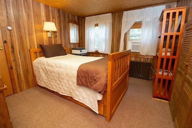 carpeted bedroom with radiator heating unit, cooling unit, and wooden walls