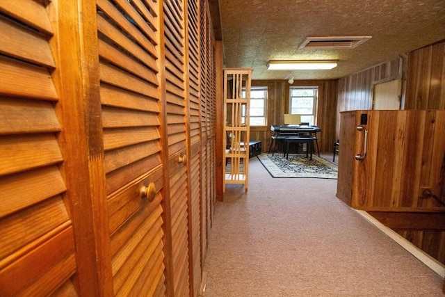 hallway with carpet, a textured ceiling, and wooden walls