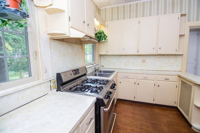 kitchen featuring stainless steel gas stove, white cabinetry, dark wood-type flooring, and sink