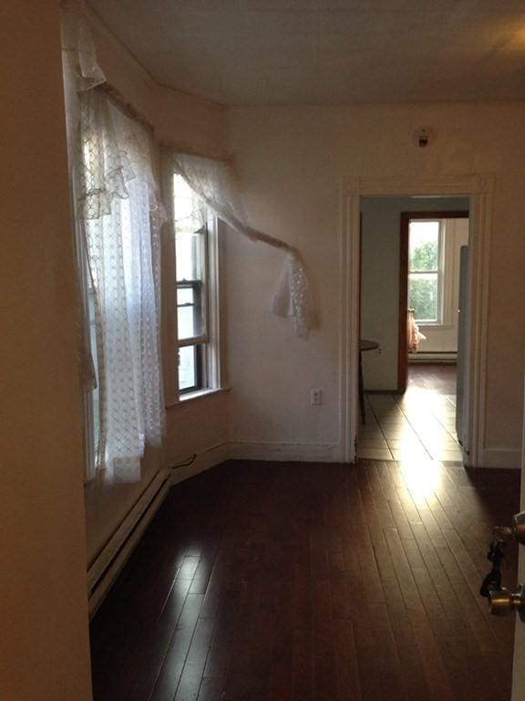 empty room featuring wood-type flooring and baseboard heating