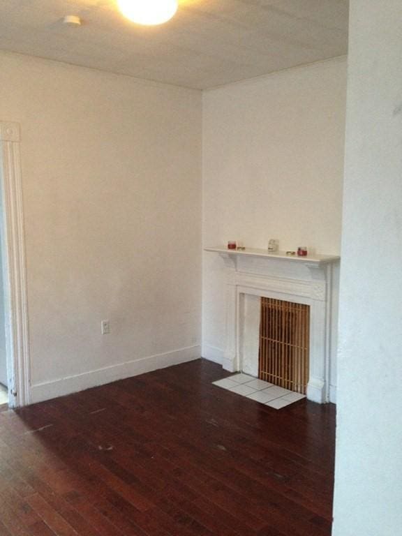 unfurnished living room with dark wood-type flooring and a tiled fireplace