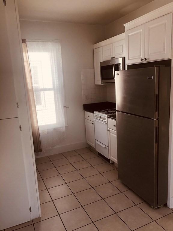 kitchen with tasteful backsplash, white cabinetry, light tile patterned floors, and stainless steel appliances