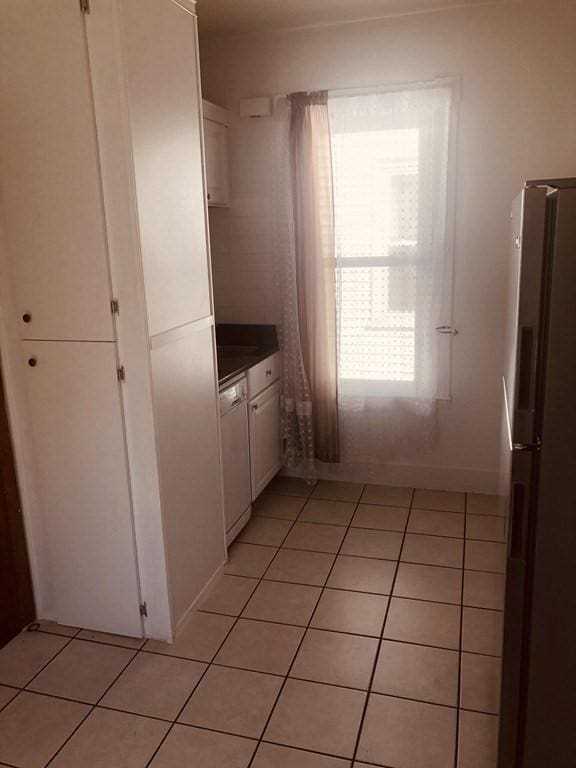 kitchen with stainless steel fridge, dishwasher, white cabinets, and light tile patterned floors